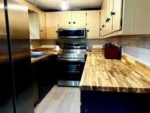 Eine Küche mit Holzschränken, Edelstahlgeräten und einer Holz Arbeitsplatte.