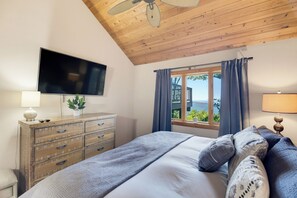 Ein Schlafzimmer mit einem Bett, einem Schminktisch, einem Fernseher und einem Fenster mit Vorhängen.