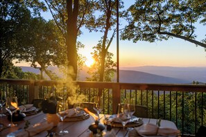 An outdoor dining area with a table set for two, overlooking a mountainous landscape. - Sunset Views, Hot Tub, and Firepit in Wintergreen! (Wintergreen Resort)