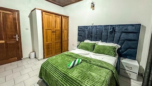 Un dormitorio con cama, mesita de noche, armario y lámpara de techo.
