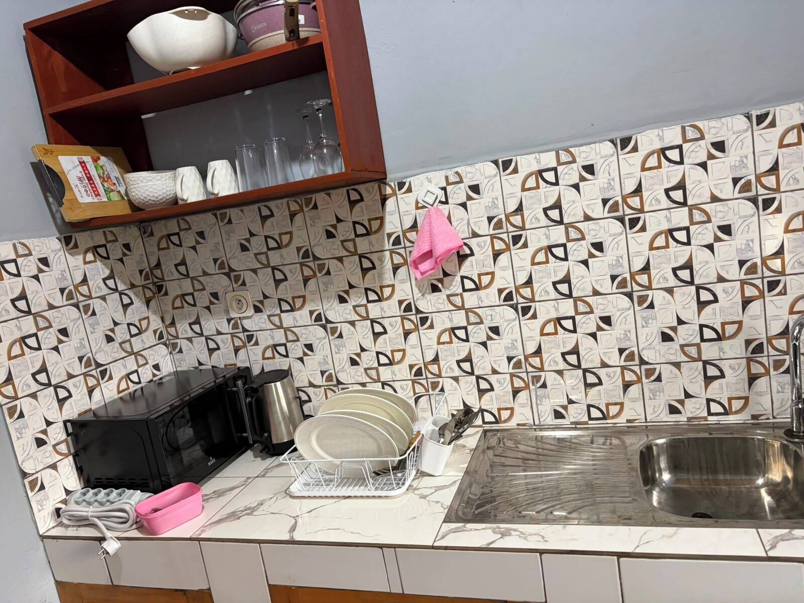 Una cocina con salpicadero estampado, un fregadero y diversos utensilios.