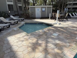 A swimming pool with lounge chairs and a small building with a door and a sign. - One Bedroom Beach Oasis in Ocean Creek Resort (Myrtle Beach)