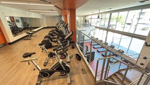 Ein Fitnessstudio mit Cardiogeräten, Krafttrainingsgeräten und Blick durch große Fenster nach draußen.