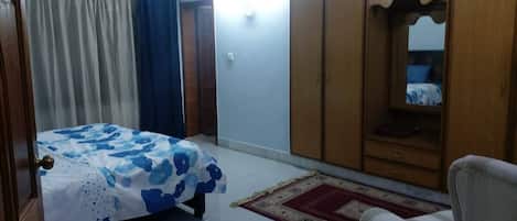 Une chambre à coucher avec un lit, une armoire, une chaise et un miroir.