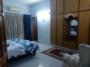 Ein Schlafzimmer mit Bett, Kleiderschrank, Sessel und Spiegel.