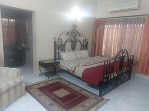 Um quarto com uma cama, mesa de cabeceira e um tapete vermelho estampado.