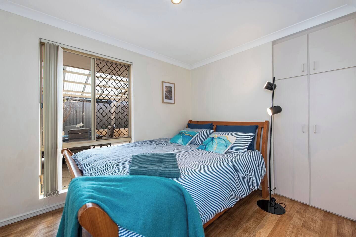 A bedroom with a bed, a chair, a wardrobe, and a window with a view.