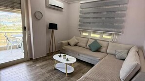 Un salon moderne avec un canapé, une table basse et une fenêtre équipée de stores.