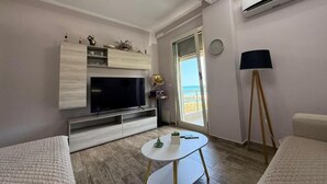 A modern living room with a flat-screen TV, a small round table, and a sofa. - Coco Apartment (Radhimë)