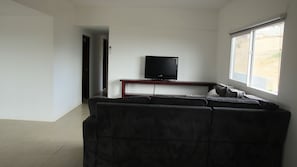 A living room with a television on a stand, a sofa, and a window.