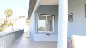 A balcony with a view of the street, a window, and a railing.