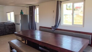 A kitchen with a large wooden table, a bench, and a refrigerator.
