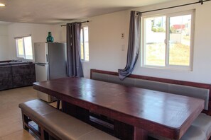 A kitchen with a large wooden table, a bench, and a refrigerator.