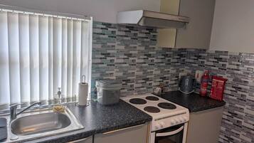 A kitchen with a sink, stove, and a window with blinds.