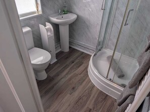 Et badeværelse med toilet, håndvask og bruseområde.