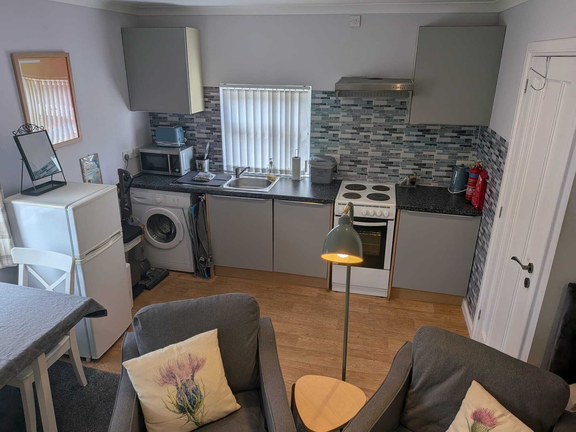 A compact kitchen with a microwave, toaster, sink, and stove.