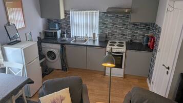 A compact kitchen with a microwave, toaster, sink, and stove.
