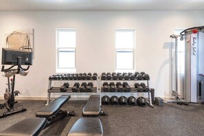 Ein Fitnessstudio mit Gewichten, Hanteln, Bänken und Trainingsgeräten.