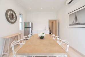 Eine moderne Küche mit einem Edelstahl-Kühlschrank, einem Holzesstisch mit weißen Stühlen und einer großen Uhr an der Wand.