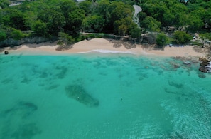 An aerial view of a beach with clear turquoise waters, a sandy shore, and dense greenery. - Portobello Villa | Contemporary Beachfront Luxury on Barbados’ West Coast (St James)