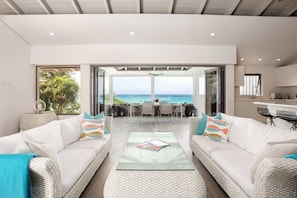 A spacious living area with a view of the ocean, a dining area, and a kitchen. - Portobello Villa | Contemporary Beachfront Luxury on Barbados’ West Coast (St James)