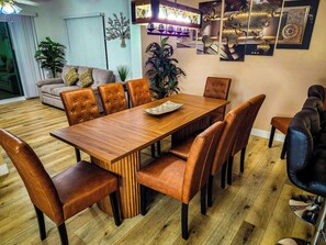 Ein Essbereich mit Holztisch, Lederstühlen, einer Couch und dekorativer Wandkunst.