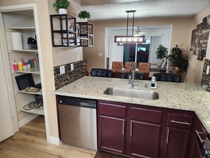 A kitchen with a dishwasher, a marble countertop, and a built-in sink. - Large Vacation House w/ Game Room 10-min Down Town (Las Vegas)