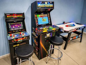 Two arcade machines, a table tennis table, and two stools in a room. - Large Vacation House w/ Game Room 10-min Down Town (Las Vegas)