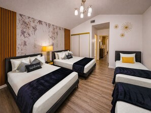 Habitación de hotel con tres camas, suelo de madera, pared de mármol y una araña.