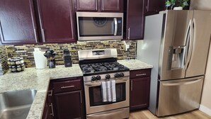 A kitchen with dark cabinets, stainless steel appliances, a microwave, stove, oven, and a refrigerator. - Large Vacation House w/ Game Room 10-min Down Town (Las Vegas)