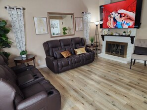 Un salon avec un canapé en cuir, une cheminée et un téléviseur fixé au mur.