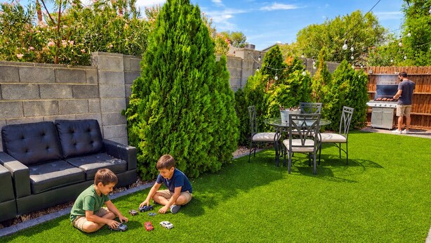 A backyard with a black outdoor sofa, a dining table with chairs, a barbecue grill, and children playing with toy cars. - Large Vacation House w/ Game Room 10-min Down Town (Las Vegas)