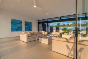 A modern living room with a sectional sofa, a coffee table, and artwork on the walls. - Monkey Ridge | Contemporary Luxury with Panoramic Sea Views (Lower Carlton)