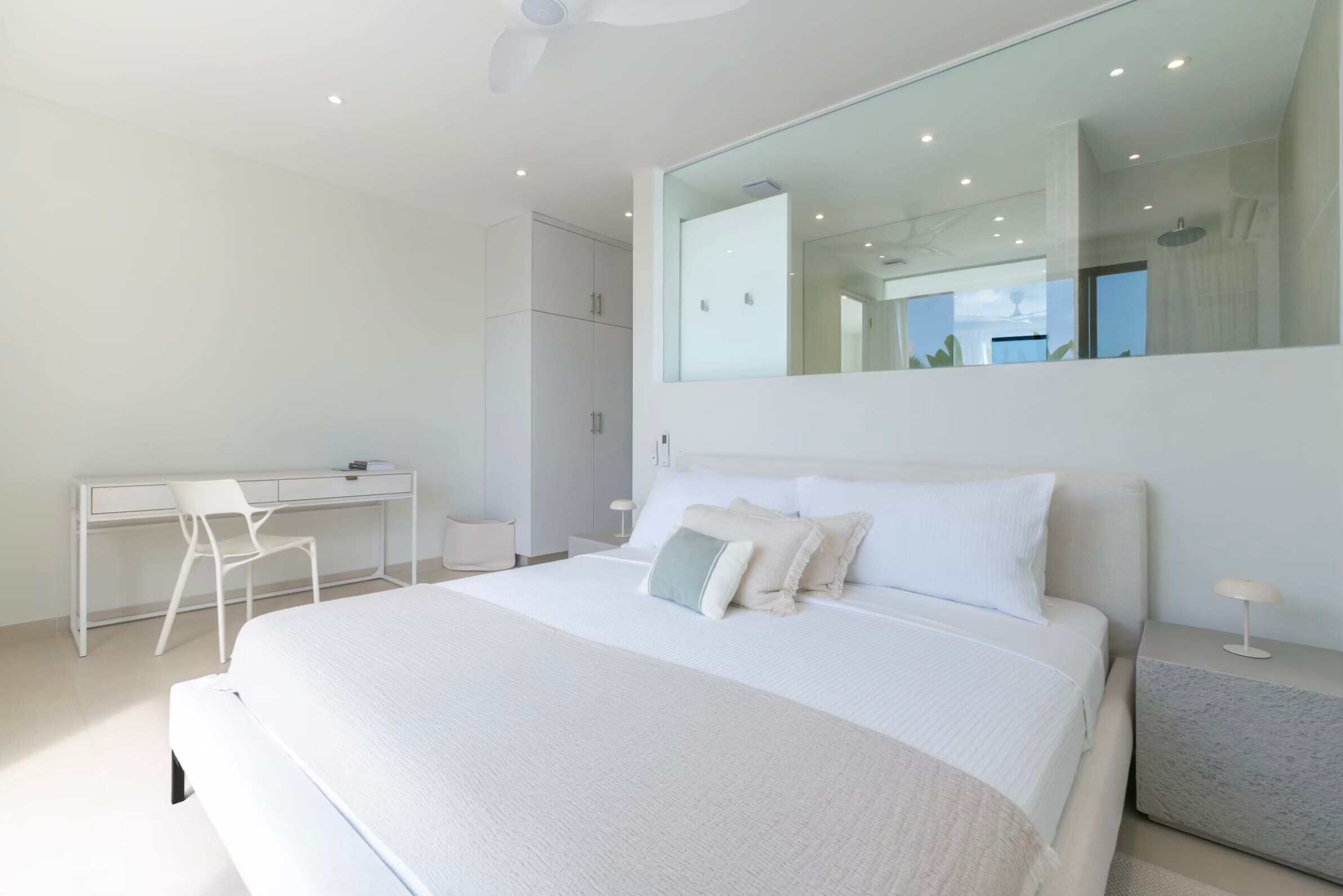 A modern bedroom with a large bed, a desk, and a wardrobe.