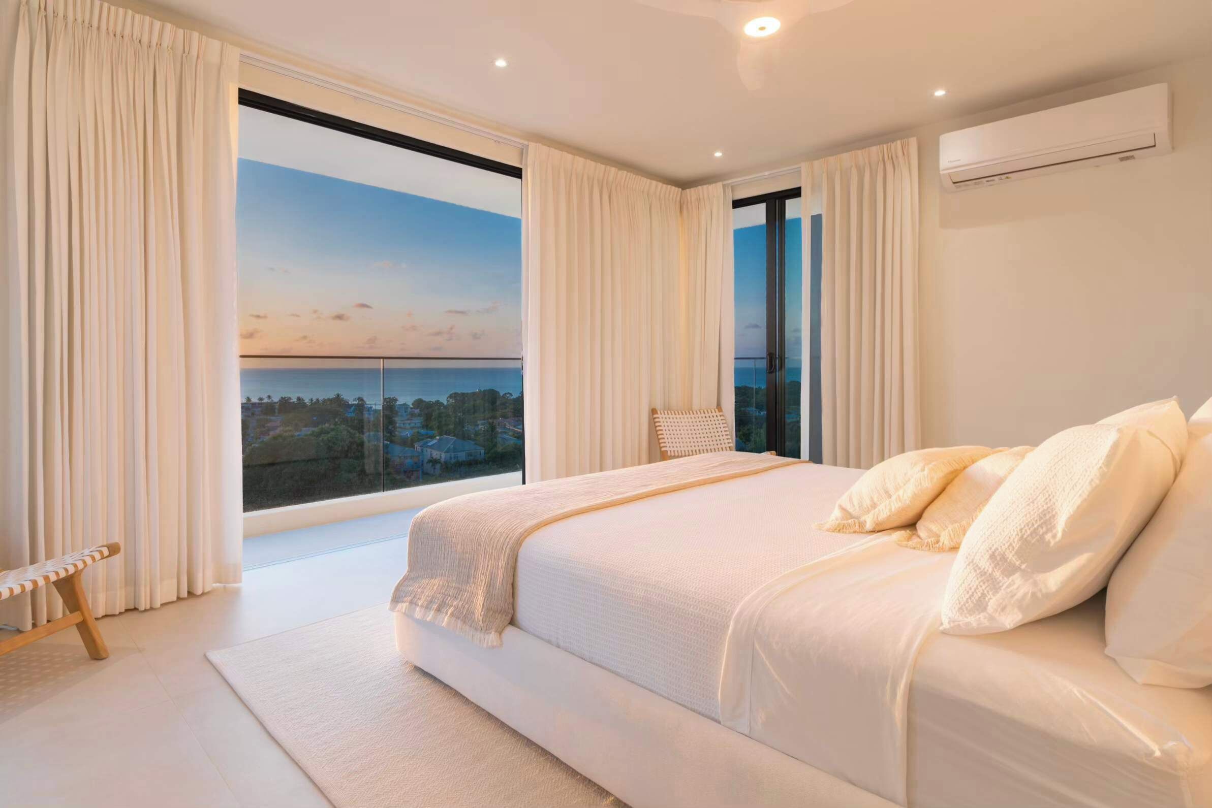 A bedroom with a large bed, a view of the sea, and a balcony.