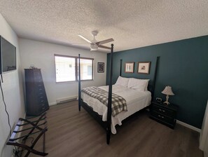 A four-poster bed with a checkered blanket, a bedside table with a lamp, and a dresser with a mirror. - Paw's For Awhile - 55 Ponderosa (Plumas Eureka)