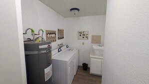 A laundry room with a water heater, washing machine, dryer, and a wall-mounted security camera. - Paw's For Awhile - 55 Ponderosa (Plumas Eureka)