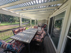 A covered patio with a table and chairs, a grill, and a view of a golf course. - Pondy - 101 Ponderosa (Plumas Eureka)