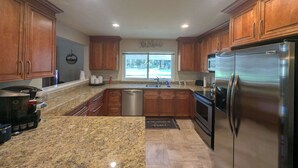 A modern kitchen with granite countertops, stainless steel appliances, and wooden cabinets. - Pondy - 101 Ponderosa (Plumas Eureka)