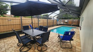 An outdoor patio with a pool, a table and chairs, and a covered seating area. - 3-bedroom house in peaceful Port Richey with AC comfort (Port Richey)