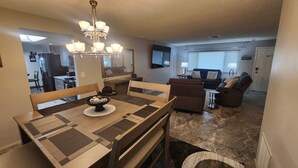A dining area with a wooden table and chairs, a chandelier, and a bowl of decorative items. - 3-bedroom house in peaceful Port Richey with AC comfort (Port Richey)
