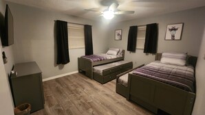 A bedroom with two single beds, a desk, and a ceiling fan. - 3-bedroom house in peaceful Port Richey with AC comfort (Port Richey)