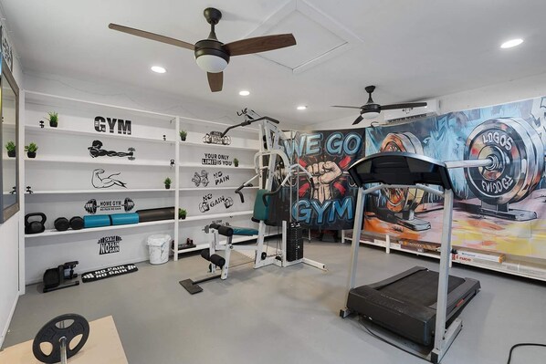 A home gym with exercise equipment, motivational wall art, and a treadmill.
