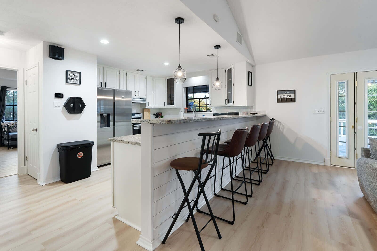 A modern kitchen with a central island, bar stools, and a view of the living area.