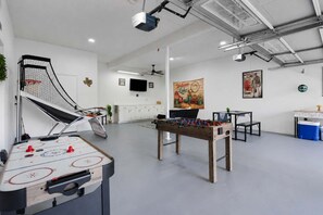 A spacious indoor area with a foosball table, a ping pong table, and a pool table.