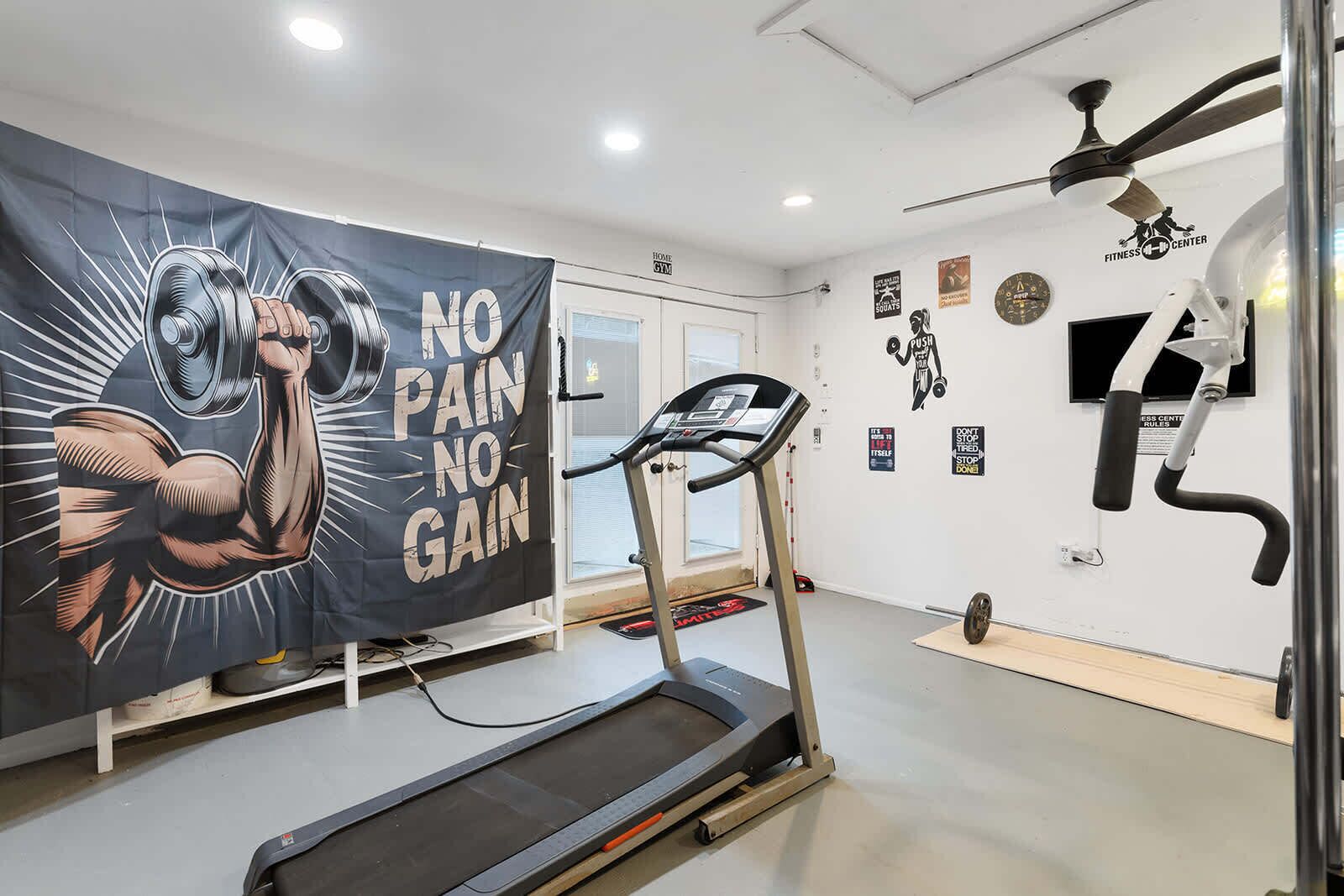 A gym with a treadmill, a wall with motivational posters, and a banner with a muscular arm illustration.