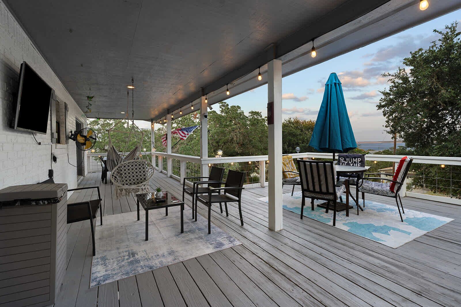 Eine überdachte Terrasse im Freien mit Grill, Sitzgelegenheit und Blick auf das Meer.