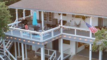 A two-story house with a covered patio, outdoor seating, and a flag.