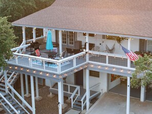 A two-story house with a covered patio, outdoor seating, and a flag.