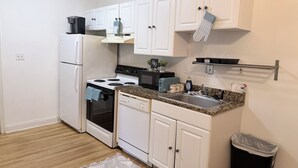 A compact kitchen with white cabinets, a stove, a microwave, and a toaster.
